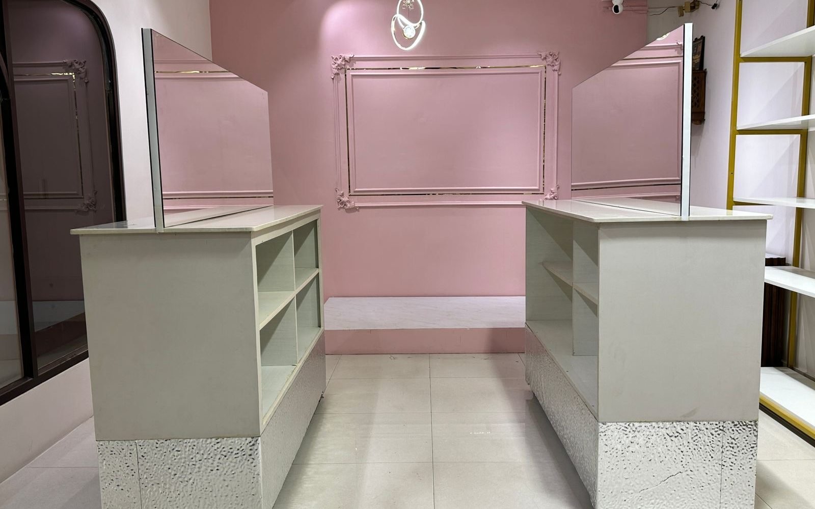 The pink feature wall of the Ananta Designs boutique, with raised moulding and a pendant light, flanked by the two display counters.