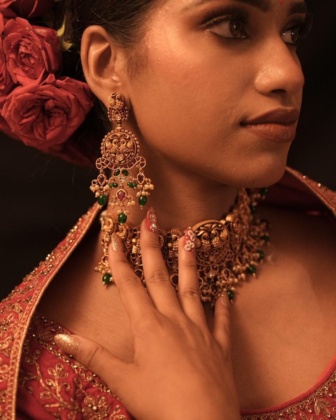 Close portrait of bridal makeup with gold temple jewellery and roses in the hair.